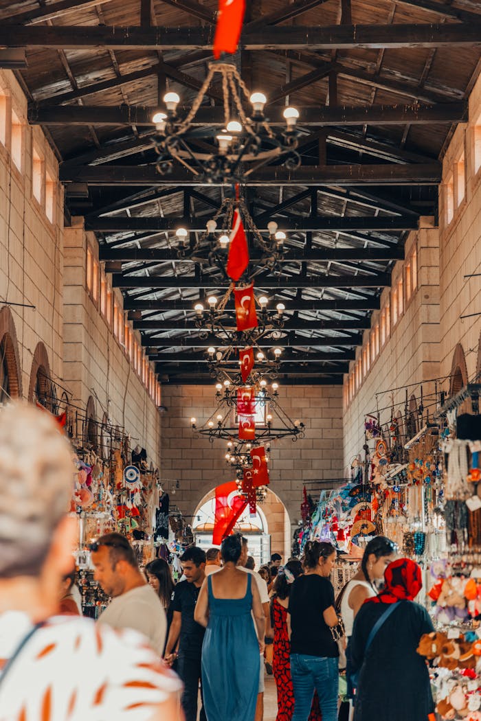 Vibrant indoor market in Çanakkale, Türkiye featuring Turkish flags and bustling crowd.